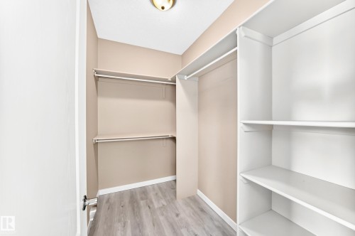 Walk-in closet with built-in shelving, hanging rods, and wood-finish flooring - 16227 64 Street Nw, Edmonton, AB - Indoor With Storage