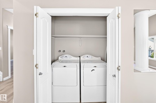 Dedicated laundry closet with bi-fold doors and overhead shelving - 16227 64 Street Nw, Edmonton, AB - Indoor Photo Showing Laundry Room