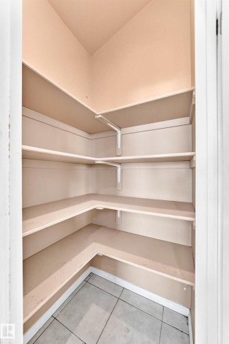 Built-in shelving with multiple levels, corner configuration, and tile flooring - 16227 64 Street Nw, Edmonton, AB - Indoor With Storage