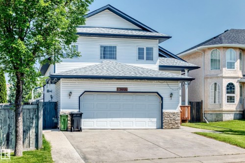 White siding exterior with a dark shingled roof, featuring a double garage and stone facade accents - 16227 64 Street Nw, Edmonton, AB - Outdoor