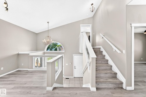 Vaulted ceiling with an arched window, wood-finish flooring, and a chandelier - 16227 64 Street Nw, Edmonton, AB - Indoor Photo Showing Other Room