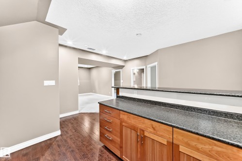 Wood-finish flooring, built-in cabinetry, dark stone-finish countertops, recessed lighting, and neutral wall paint - 16227 64 Street Nw, Edmonton, AB - Indoor