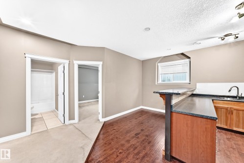 Wet bar with wood cabinetry and dark countertops, wood-finish flooring, and recessed lighting - 16227 64 Street Nw, Edmonton, AB - Indoor