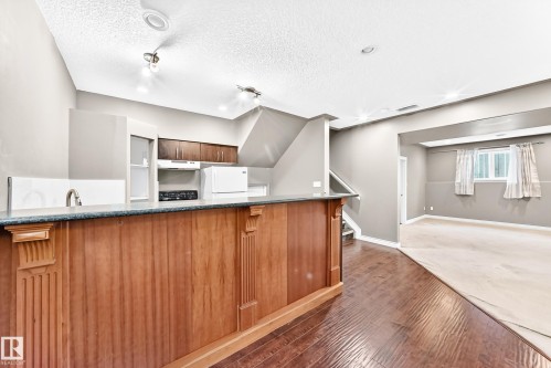 Kitchenette with wood-finish cabinetry, dark countertop, and integrated appliances - 16227 64 Street Nw, Edmonton, AB - Indoor Photo Showing Kitchen