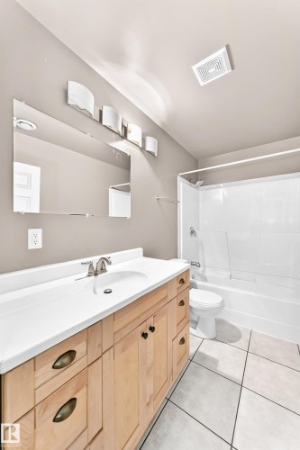 Light wood-finish vanity with a white countertop and integrated sink - 16227 64 Street Nw, Edmonton, AB - Indoor Photo Showing Bathroom