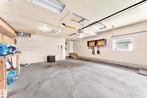 Concrete flooring, fluorescent overhead lighting, wall-mounted heater, and interior window - 16227 64 Street Nw, Edmonton, AB - Indoor Photo Showing Garage