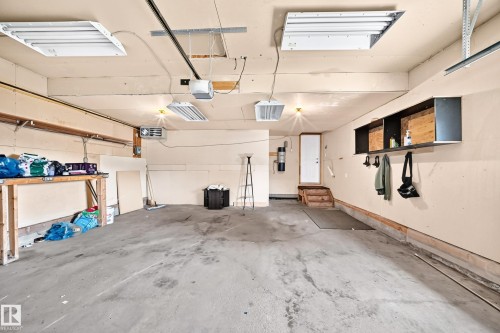 Concrete flooring, built-in shelving, overhead lighting, interior access door, and a utility heater - 16227 64 Street Nw, Edmonton, AB - Indoor Photo Showing Garage
