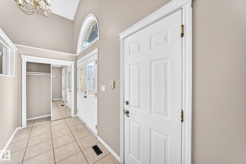Vaulted ceiling with an ornate chandelier, arched transom window, tiled flooring, and mirrored closet doors - 16227 64 Street Nw, Edmonton, AB - Indoor Photo Showing Other Room