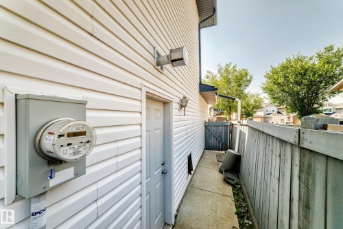 White vinyl siding exterior with a concrete pathway and wood fencing - 16227 64 Street Nw, Edmonton, AB - Outdoor With Exterior