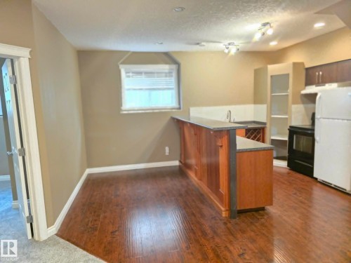 Wood-finish flooring, built-in bar, integrated wine rack, full-size refrigerator, and compact cooking range - 16227 64 Street Nw, Edmonton, AB - Indoor Photo Showing Kitchen