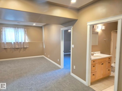 Recessed lighting, light gray carpet flooring, window with sheer curtains, wood-finish vanity with countertop sink, and tiled bathroom flooring - 16227 64 Street Nw, Edmonton, AB - Indoor Photo Showing Other Room