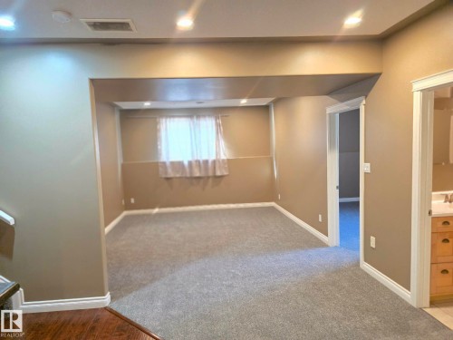 Recessed ceiling lighting illuminates the carpeted area, featuring an open doorway and a visible window - 16227 64 Street Nw, Edmonton, AB - Indoor Photo Showing Other Room