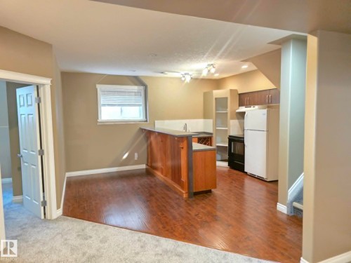 Kitchenette featuring wood-finish flooring, a built-in oven, refrigerator, and track lighting - 16227 64 Street Nw, Edmonton, AB - Indoor Photo Showing Kitchen