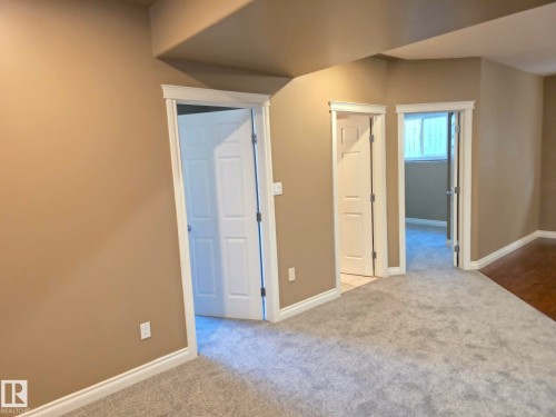 Neutral-toned walls, white trim, light gray carpeting, and wood-finish flooring - 16227 64 Street Nw, Edmonton, AB - Indoor Photo Showing Other Room