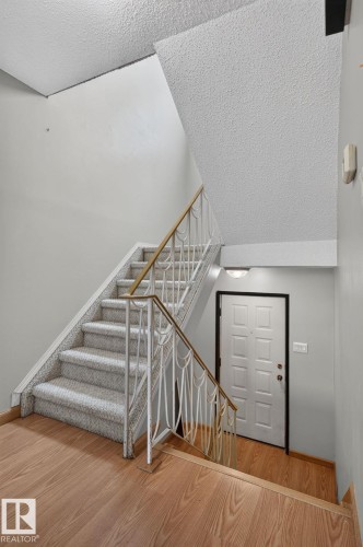 Carpeted staircase with decorative metal railing and wood-finish handrail - 10644 158 Avenue Nw, Edmonton, AB - Indoor Photo Showing Other Room