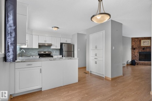 Kitchen featuring white shaker-style cabinetry, stainless steel appliances, a tile backsplash, and light-toned countertops - 10644 158 Avenue Nw, Edmonton, AB - Indoor Photo Showing Kitchen