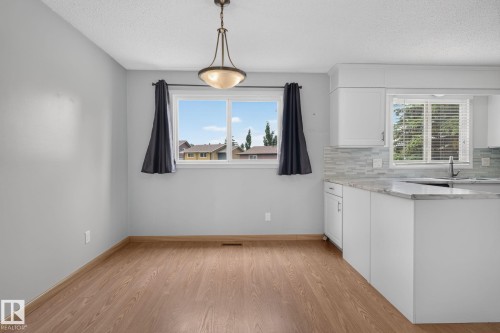 Open-concept dining area featuring wood-finish flooring, a contemporary chandelier, and a large window - 10644 158 Avenue Nw, Edmonton, AB - Indoor Photo Showing Kitchen