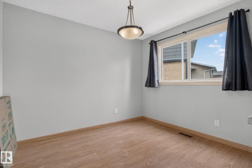 Bright room featuring a large window, neutral wall paint, wood-finish flooring, and a ceiling-mounted light fixture - 10644 158 Avenue Nw, Edmonton, AB - Indoor Photo Showing Other Room