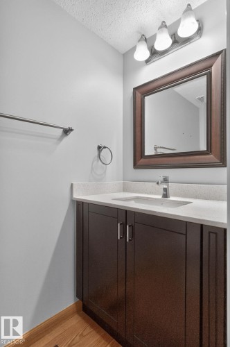 Bathroom vanity with dark wood-finish cabinetry, a light-colored countertop, and an undermount sink - 10644 158 Avenue Nw, Edmonton, AB - Indoor Photo Showing Bathroom