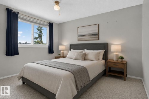 Carpeted bedroom featuring neutral wall tones, a large window, and a ceiling-mounted light fixture - 10644 158 Avenue Nw, Edmonton, AB - Indoor Photo Showing Bedroom