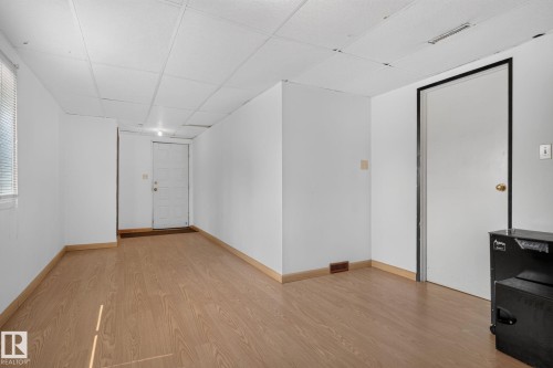 Spacious interior featuring wood-finish flooring, white walls, and a drop ceiling - 10644 158 Avenue Nw, Edmonton, AB - Indoor Photo Showing Other Room