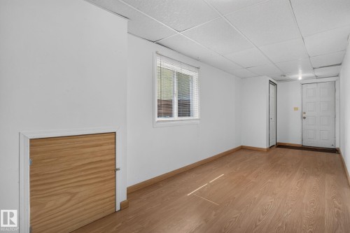 Versatile room featuring wood-finish flooring, white walls, and a drop ceiling - 10644 158 Avenue Nw, Edmonton, AB - Indoor Photo Showing Other Room