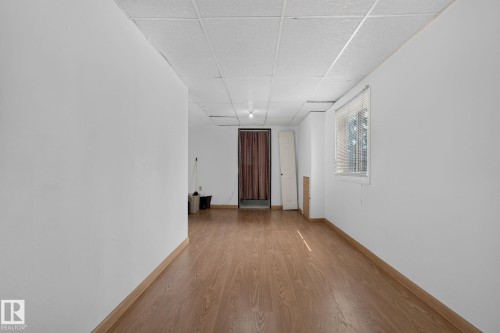 Open room featuring wood-finish flooring, white walls, and a drop ceiling - 10644 158 Avenue Nw, Edmonton, AB - Indoor Photo Showing Other Room