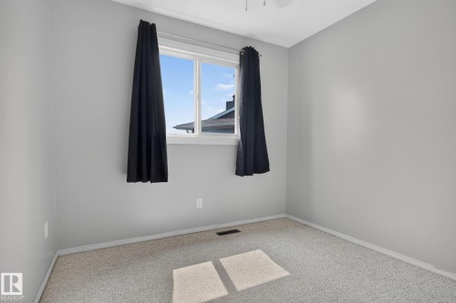 Bright room featuring a large window with white trim, light gray walls, and neutral-toned carpeting - 10644 158 Avenue Nw, Edmonton, AB - Indoor