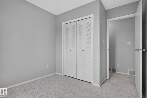 Grey-painted room with light grey carpet flooring, white bi-fold louvered closet doors, and white baseboards - 10644 158 Avenue Nw, Edmonton, AB - Indoor