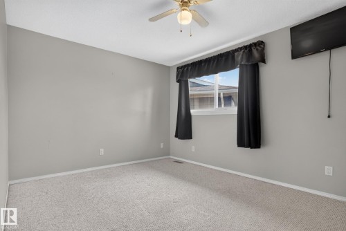 Carpeted room with a ceiling fan, light gray wall paint, and a window featuring dark curtains - 10644 158 Avenue Nw, Edmonton, AB - Indoor Photo Showing Other Room