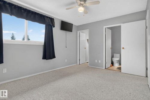 Carpeted room with a ceiling fan, two windows with white frames, and baseboard trim - 10644 158 Avenue Nw, Edmonton, AB - Indoor Photo Showing Other Room