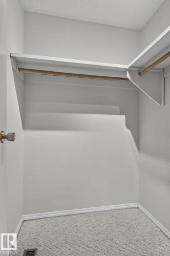 Walk-in closet with light gray walls, white shelving, and natural wood hanging rods - 10644 158 Avenue Nw, Edmonton, AB - Indoor With Storage