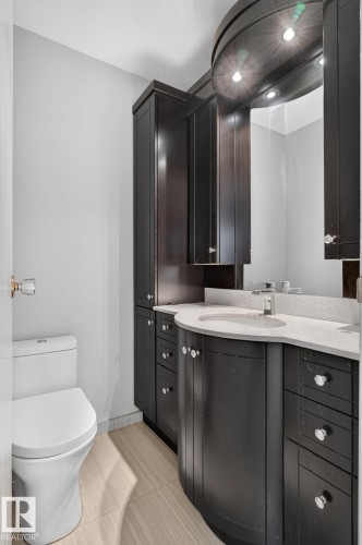 Curved vanity with an integrated sink, light-toned countertop, and dark wood-finish cabinetry - 10644 158 Avenue Nw, Edmonton, AB - Indoor Photo Showing Bathroom