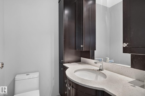 Curved vanity with an integrated sink, light-toned countertop, and chrome faucet - 10644 158 Avenue Nw, Edmonton, AB - Indoor Photo Showing Bathroom