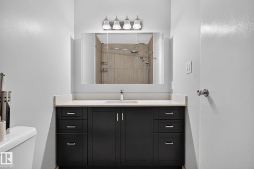 Bathroom featuring a dark wood-finish vanity with a light-toned countertop, an undermount sink, and a mirrored medicine cabinet - 10644 158 Avenue Nw, Edmonton, AB - Indoor Photo Showing Bathroom
