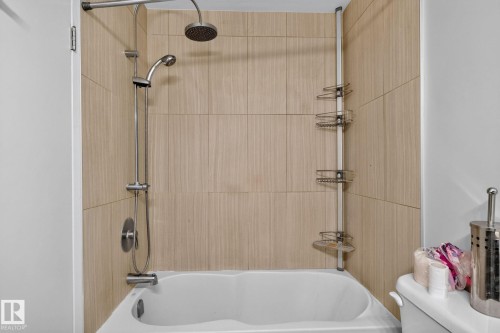Tub-shower combination featuring light wood-finish wall tiling and a stainless steel shower head with a handheld attachment - 10644 158 Avenue Nw, Edmonton, AB - Indoor Photo Showing Bathroom