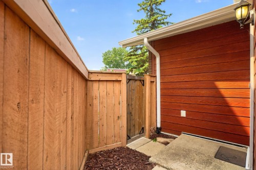Private fenced outdoor space featuring a wood-panel accent wall and concrete patio area - 10644 158 Avenue Nw, Edmonton, AB - Outdoor With Exterior