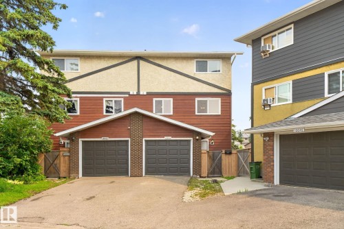 Multi-level townhome featuring a two-car garage with individual doors, brown siding, and brick accents - 10644 158 Avenue Nw, Edmonton, AB - Outdoor