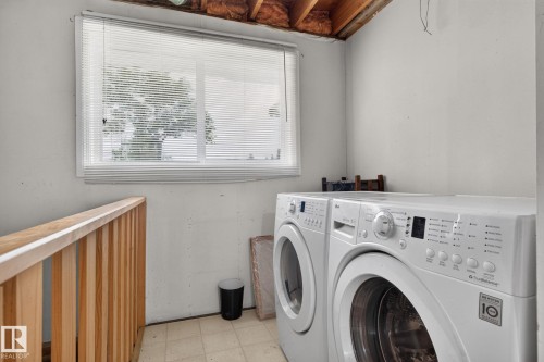 Laundry area featuring a window with horizontal blinds, light-toned flooring, and a wooden banister - 10644 158 Avenue Nw, Edmonton, AB - Indoor Photo Showing Laundry Room