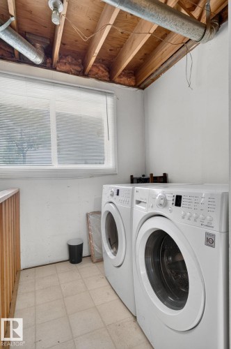 Dedicated laundry area featuring a large window with blinds, tile flooring, and a wooden railing - 10644 158 Avenue Nw, Edmonton, AB - Indoor Photo Showing Laundry Room