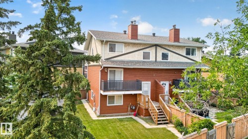 Rear exterior featuring a red siding lower level, stucco upper level, and an upper-level balcony with black railings - 10644 158 Avenue Nw, Edmonton, AB - Outdoor With Balcony