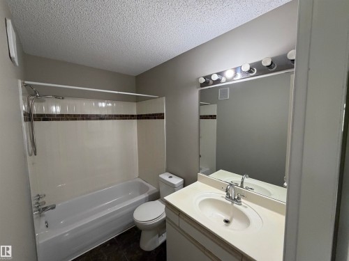 Bathtub with a shower fixture, mosaic tile accent, single vanity with an integrated sink, and a large mirror with overhead lighting - 1535 80A Street Nw, Edmonton, AB - Indoor Photo Showing Bathroom