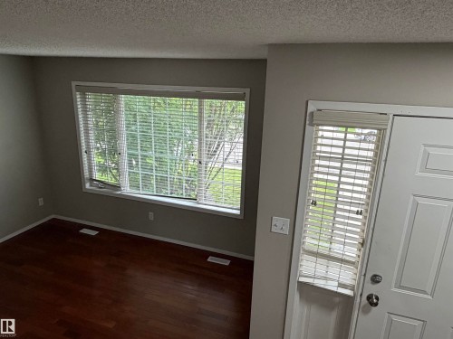Wood-finish flooring, light gray wall color, multiple windows, and white trim throughout - 1535 80A Street Nw, Edmonton, AB - Indoor Photo Showing Other Room