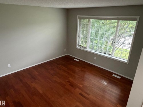 Hardwood flooring, neutral wall tones, large window with blinds, and white trim - 1535 80A Street Nw, Edmonton, AB - Indoor Photo Showing Other Room