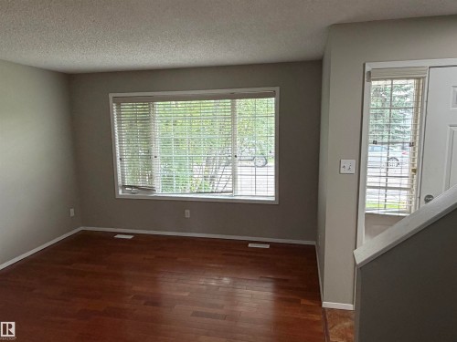Wood-finish flooring, multiple windows with blinds, and neutral wall paint - 1535 80A Street Nw, Edmonton, AB - Indoor Photo Showing Other Room
