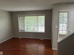 Wood-finish flooring, multiple windows with blinds, and neutral wall paint - 