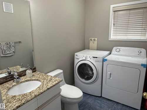 Vanity with granite countertop, integrated sink, and mosaic tile backsplash - 1535 80A Street Nw, Edmonton, AB - Indoor Photo Showing Laundry Room