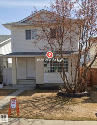 Two-story residential structure with light-colored siding, a front entry porch, and a landscaped front yard with a tree and a stone-edged planter - 1535 80A Street Nw, Edmonton, AB - Outdoor