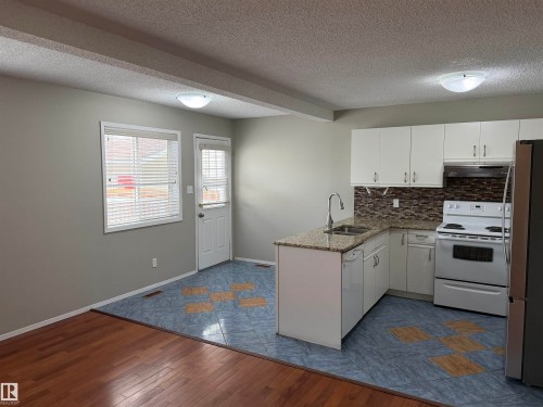 Kitchen featuring white cabinetry, granite-style countertops, stainless steel appliances, and tile backsplash - 1535 80A Street Nw, Edmonton, AB - Indoor Photo Showing Kitchen