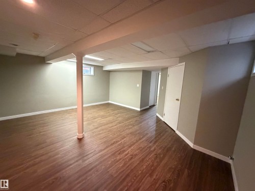 Spacious room featuring wood-finish flooring, light-toned walls, and a drop ceiling with recessed lighting - 1535 80A Street Nw, Edmonton, AB - Indoor